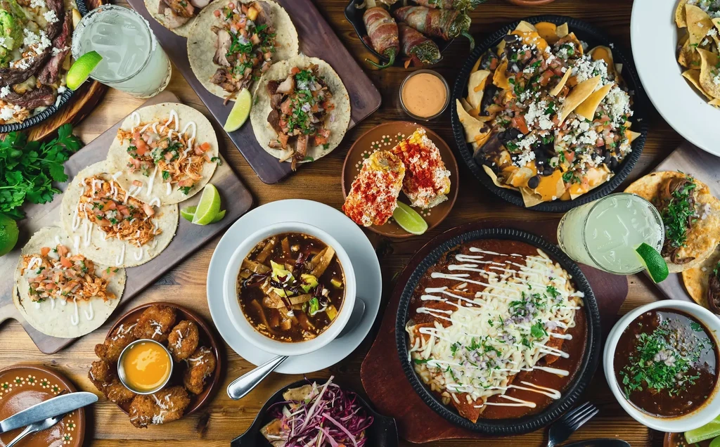 Wooden table completely covered with an abundant spread of Mexican dishes.