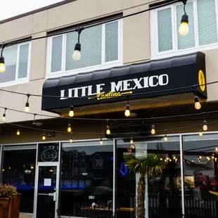 Restaurant Little Mexico Cantina exterior with black awning and Edison lights.