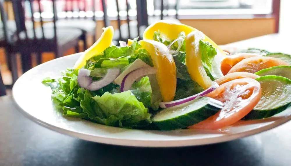 Fresh garden salad with lettuce, onions, bell pepper, cucumber, tomatoes.
