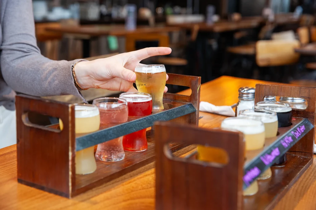 Hand picks a golden drink from a wooden flight.