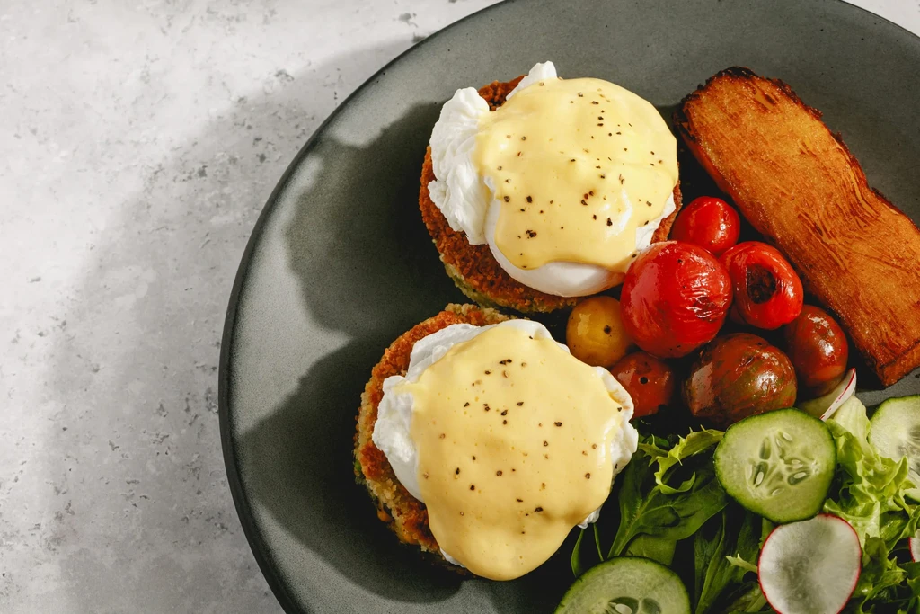 Plated Eggs Benedict with roasted tomatoes, toast, and fresh green salad.