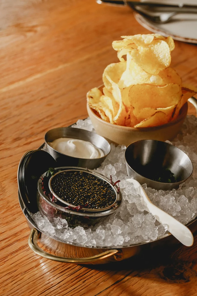 Black caviar, potato chips, and dips on a platter of ice.