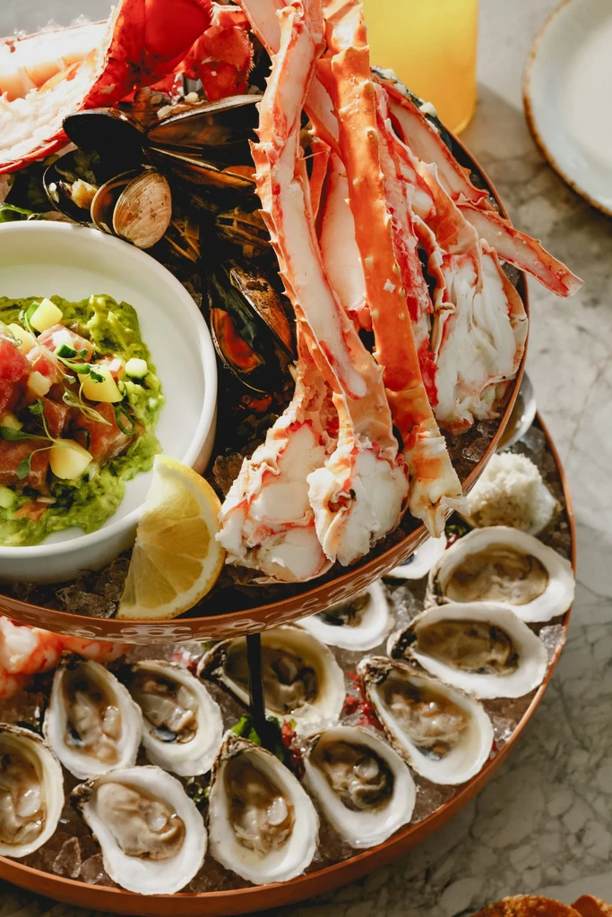 Multi-tiered seafood tower with crab, lobster, oysters, mussels, and tartare.