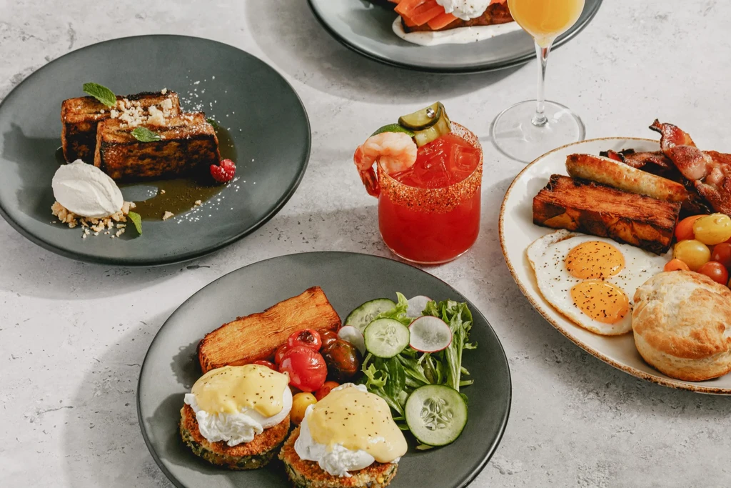 Overhead shot of various well-plated breakfast and brunch dishes and drinks.