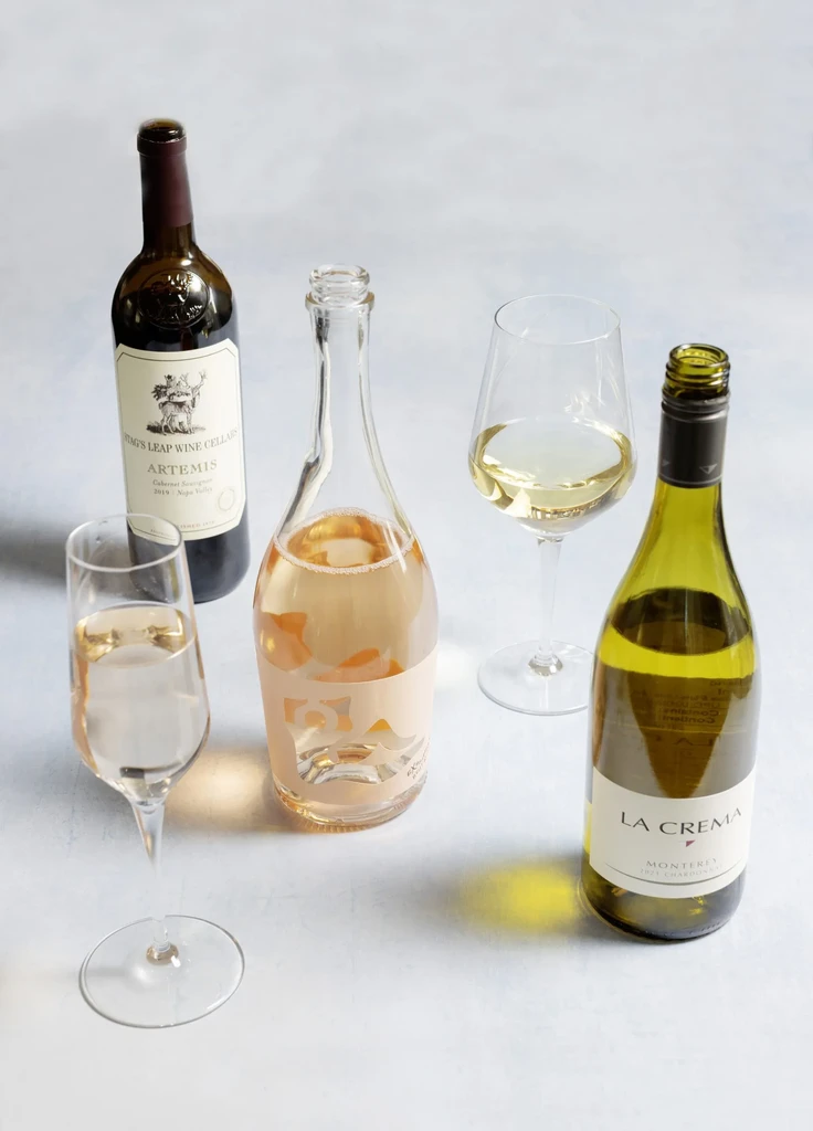 Stag's Leap, La Crema, and rosé wine bottles with two glasses.
