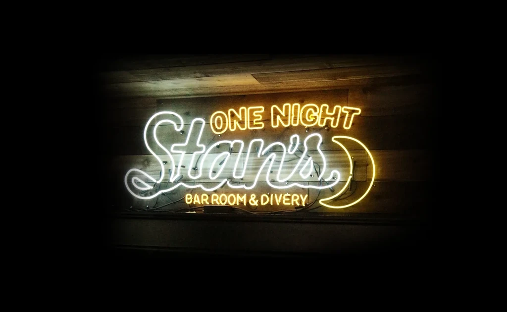 Neon sign 'ONE NIGHT Stan's BAR ROOM & DIVERY' and crescent moon.