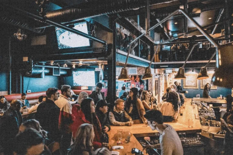 Busy multi-level bar interior with many patrons socializing.