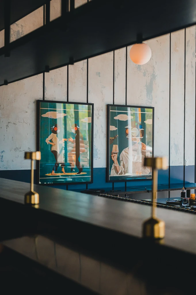 Modern restaurant bar interior with golden lamps and framed artwork.