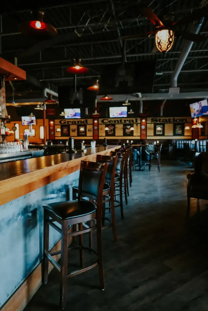 Dimly lit bar with wooden counter, stools, and "Grand Central Station" sign.