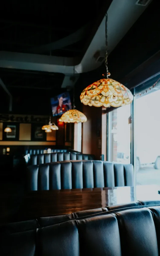 Warm, retro restaurant interior with dark booths and stained-glass lamps.
