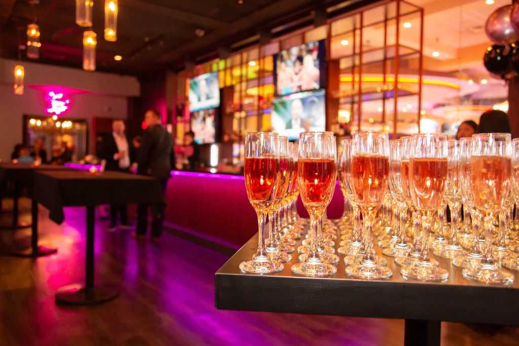 Rows of pink champagne flutes in a lively, modern bar.
