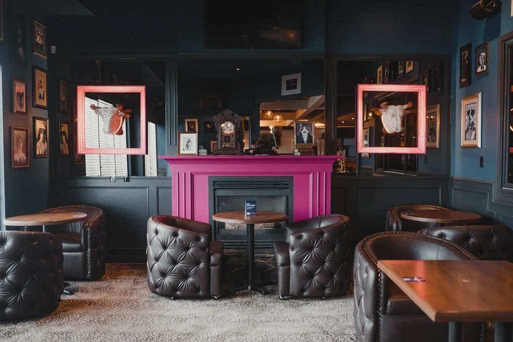Quirky restaurant lounge with pink fireplace, navy walls, and animal art.