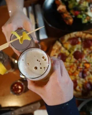 Overhead shot of two hands toasting a cocktail and a beer.