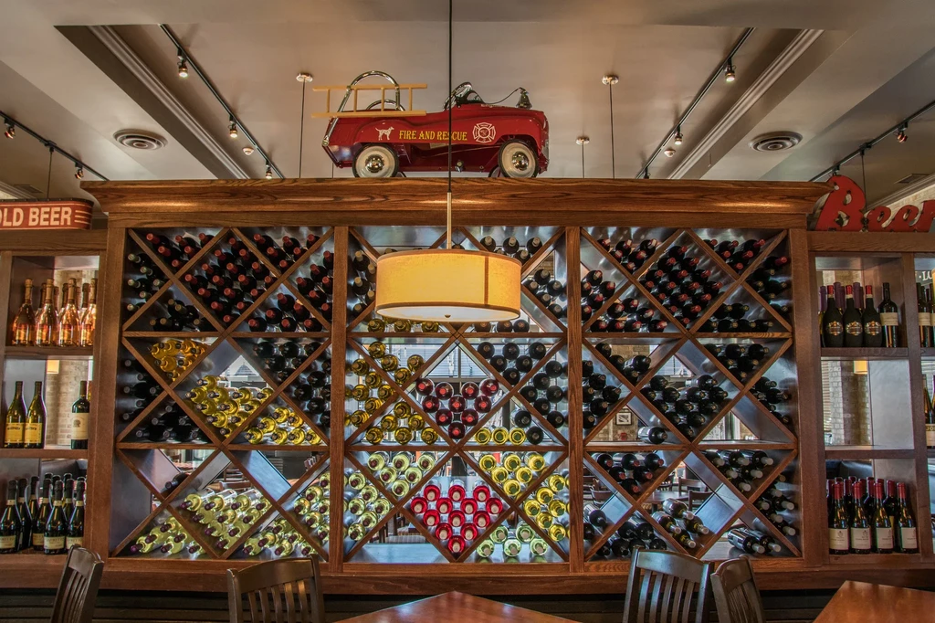 Elaborate wine rack, red toy fire truck, beer shelves in restaurant.
