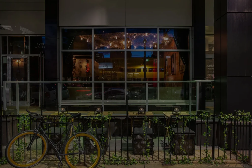 Night view of a restaurant's glowing windows, outdoor patio, and bicycle.