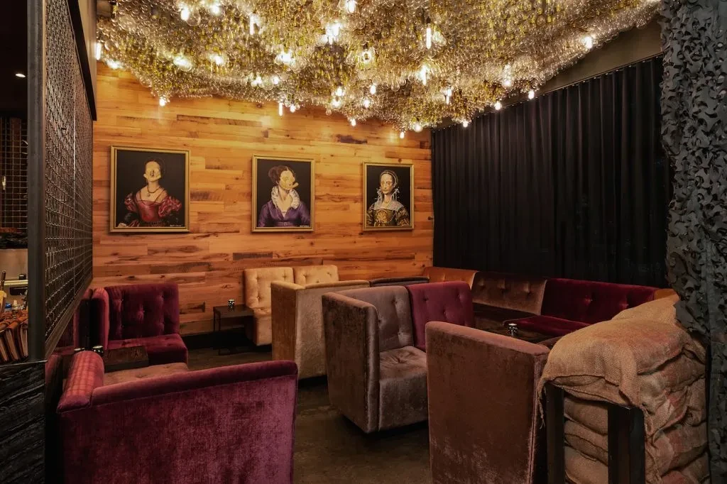 Stylish lounge with cloud-like glass ceiling lights and obscured historical portraits.