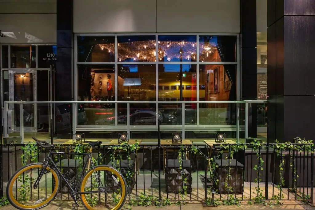 Restaurant exterior at dusk with a lit patio and bicycle.
