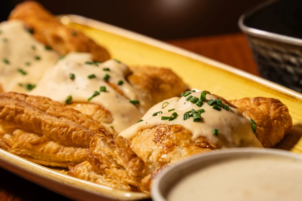 Savory golden flaky pastries with creamy sauce and chives.
