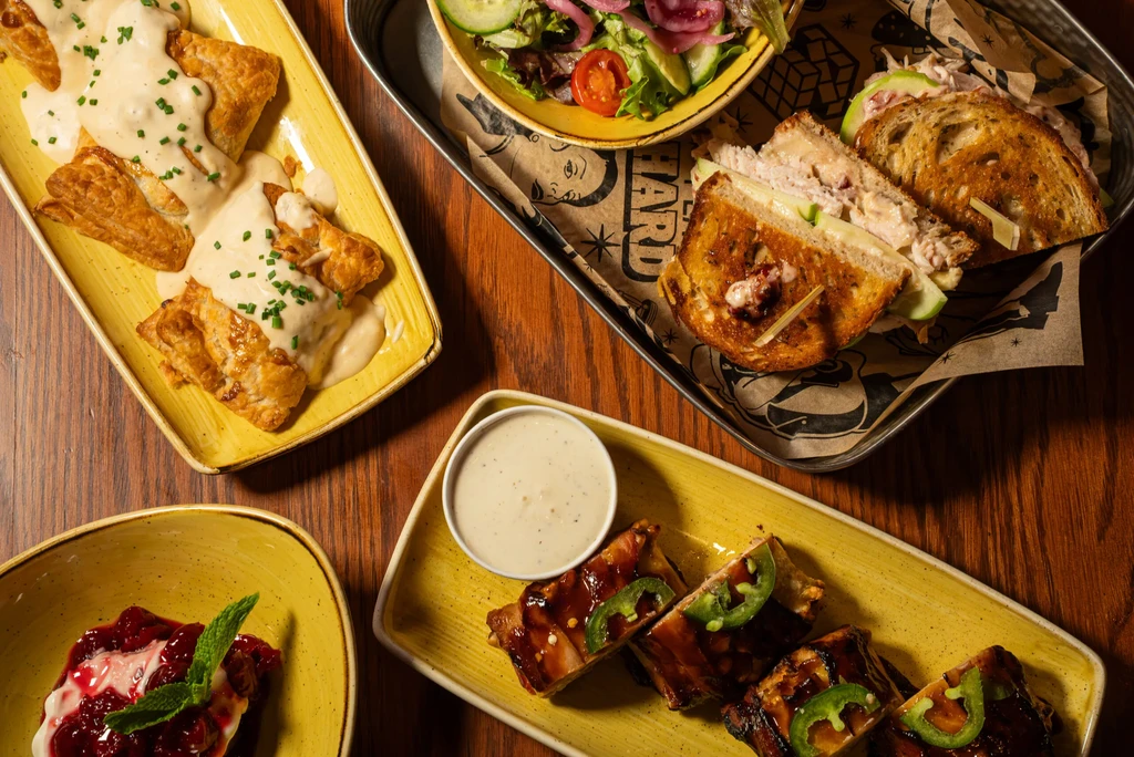 Assortment of plated meals and dessert on a dark wooden table.