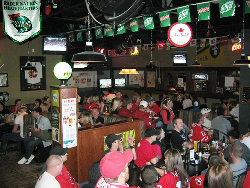 Bustling sports bar interior, many patrons in red shirts and sports decor.
