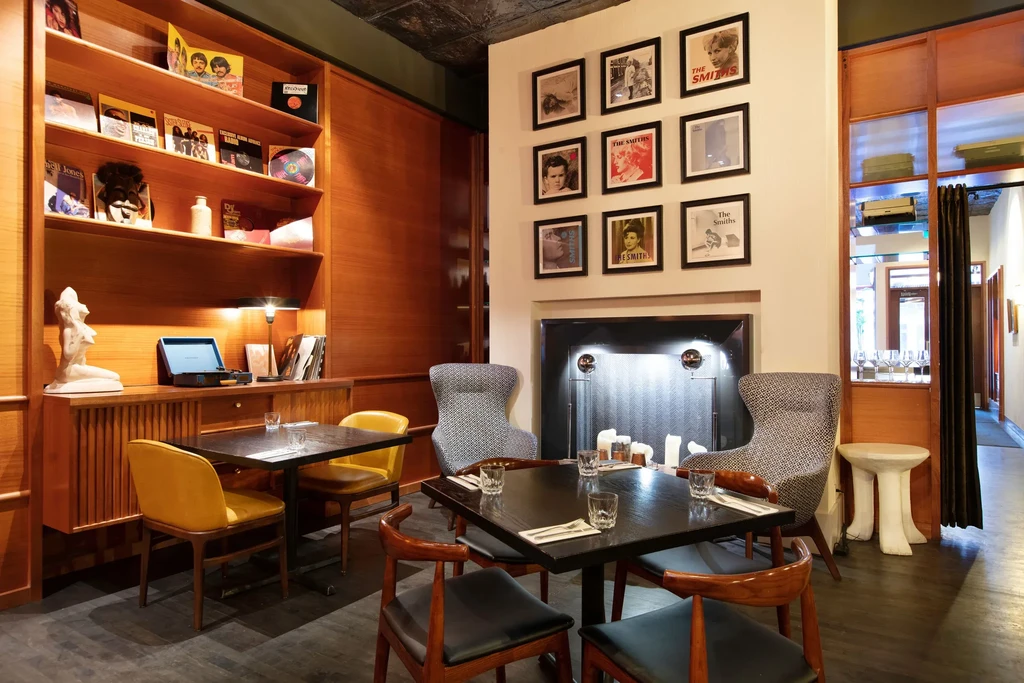 Cozy restaurant and lounge with vinyl records, dining, and Smiths art.