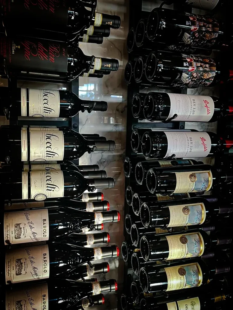 Neatly arranged dark wine bottles with various labels on a large rack.