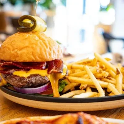 Stacked gourmet burger with melted cheese, bacon, and golden fries.