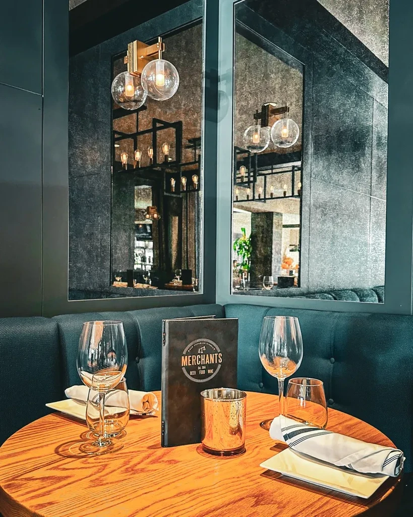 Modern restaurant corner setting with set table, menu, booth, and mirrors.