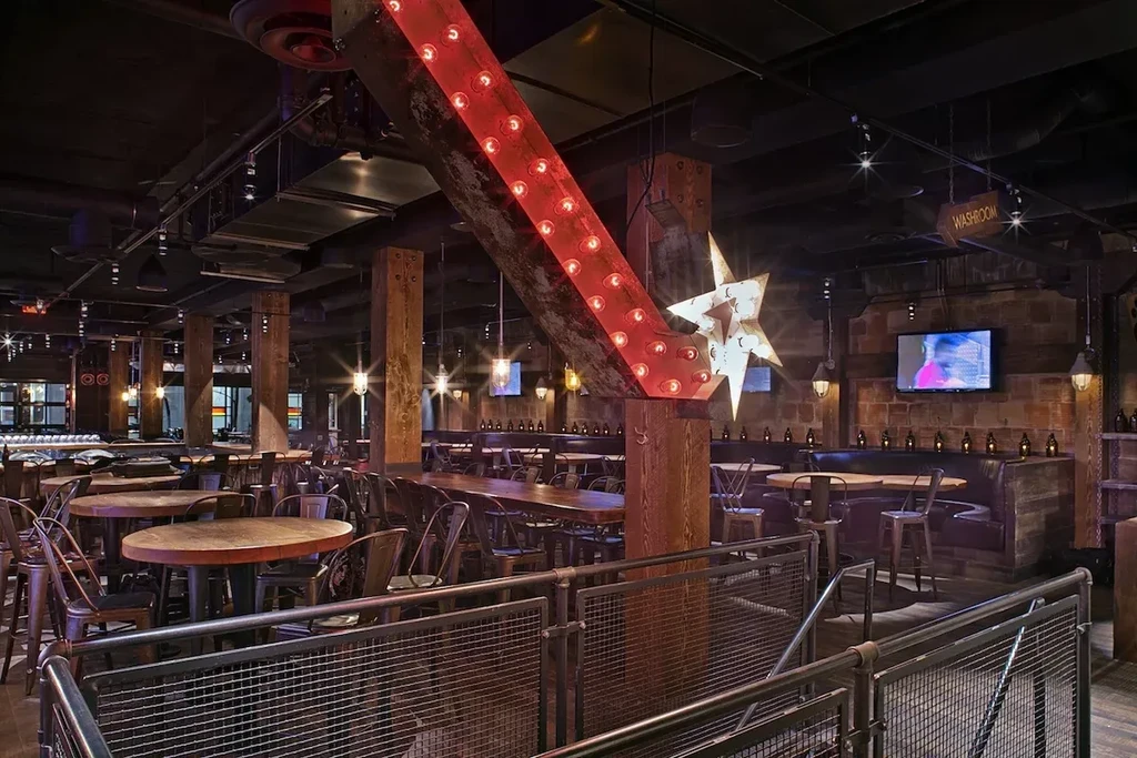 Industrial-rustic restaurant interior with red arrow sign and star light.