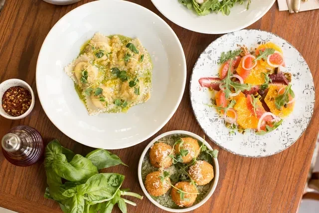 Various dishes: pasta, colorful salads, and fried items on wooden table.