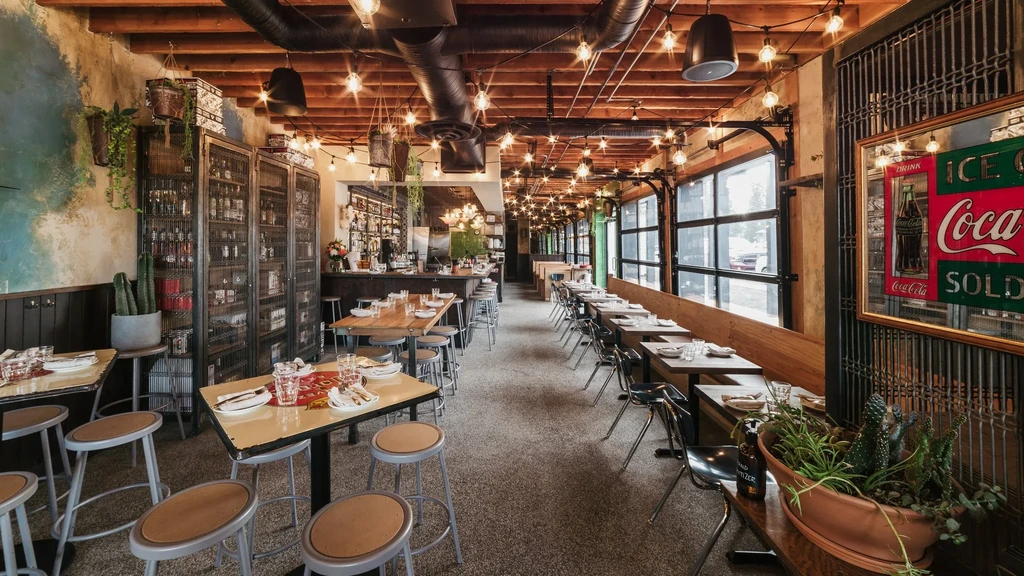 Spacious restaurant interior with industrial decor, warm lighting, and varied seating.