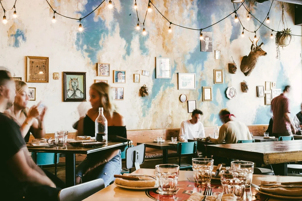 Warm, bustling restaurant with cloud mural, eclectic decor, and indistinct diners.