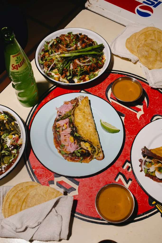 Overhead view of a table with a crispy taco, Mexican dishes, and drinks.
