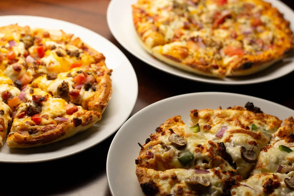 Three pizzas, two with meat and one with vegetable toppings.