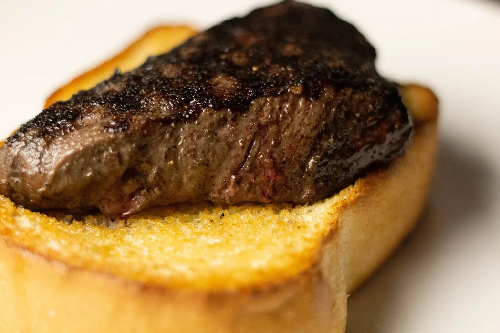Seared medium-rare steak with grill marks on golden toast.