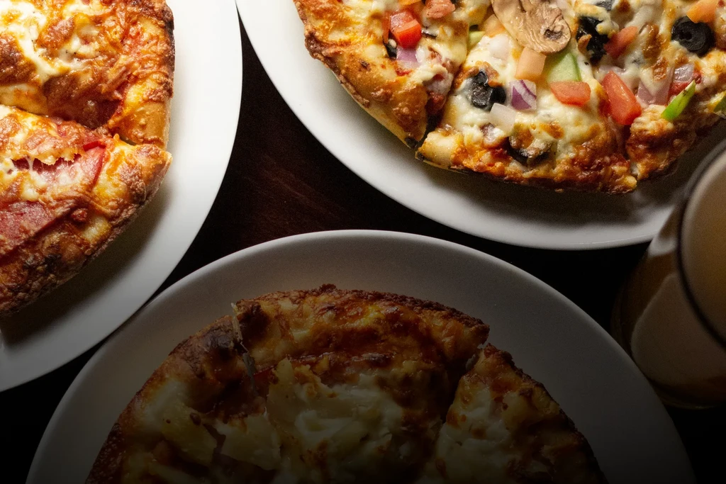 Overhead shot of three pizzas: pepperoni, veggie, and cheese, with beer.