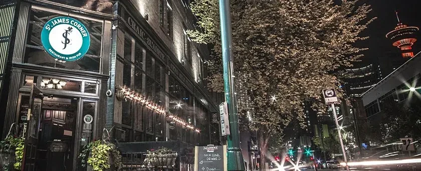 Illuminated St. James Corner Irish Pub exterior at night with Calgary Tower.