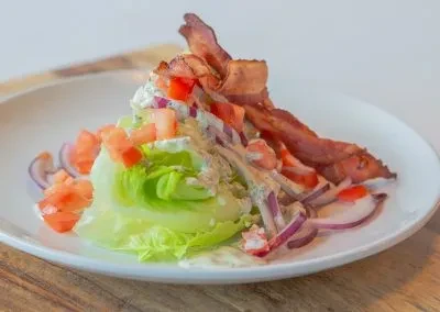 Crisp wedge salad, creamy dressing, bacon, tomatoes, red onions.