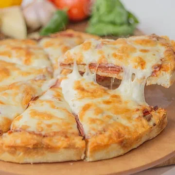 A slice of cheesy meat pizza is lifted, showing stretchy cheese.