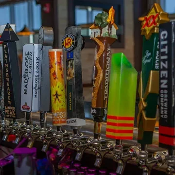 A close-up of a diverse row of unique beer tap handles.