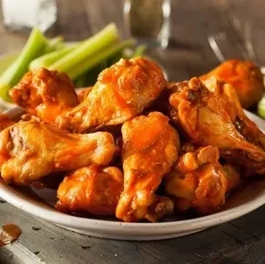Piled high reddish-orange buffalo chicken wings with celery.