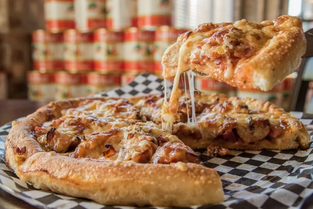 Deep-dish pizza slice lifted, showing a prominent cheese pull.
