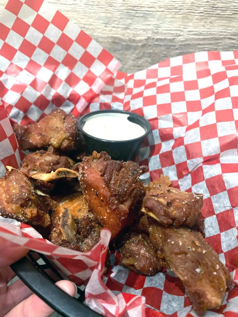 Hand holding basket of golden-brown deep-fried seasoned pork.