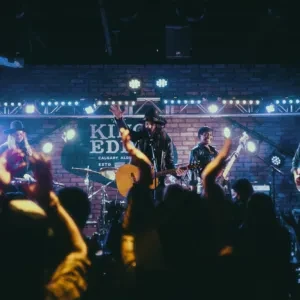 Band performs on stage under blue lights to an energetic crowd.