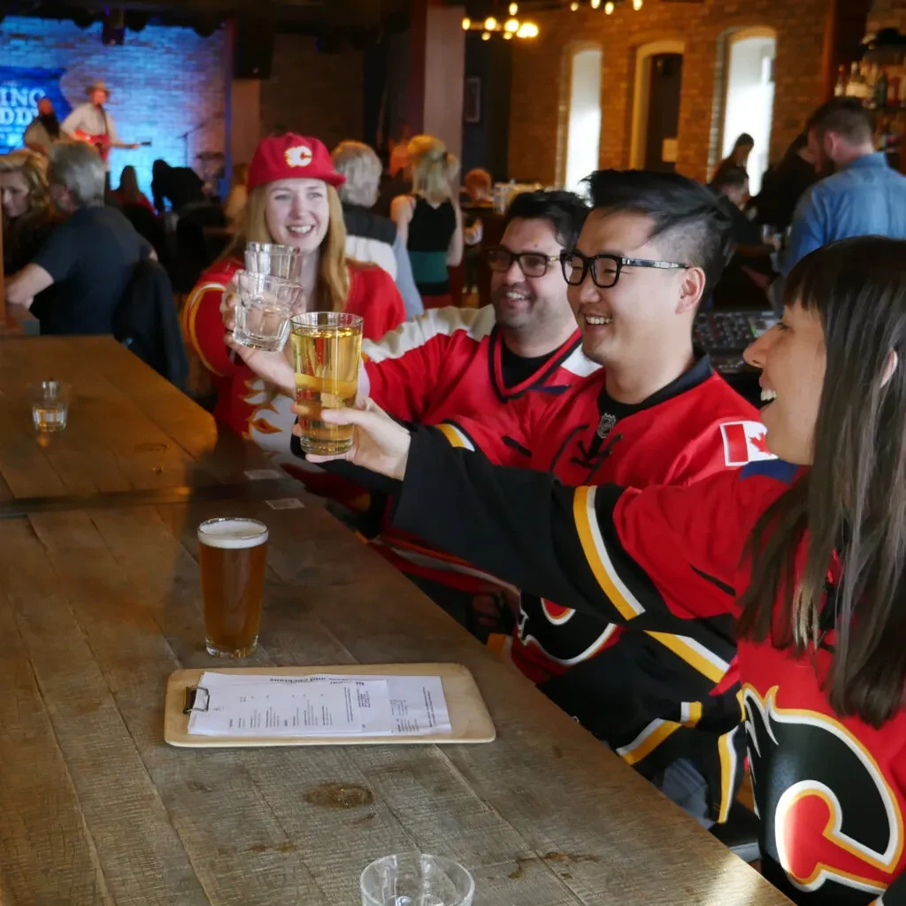 Four people in red jerseys toast at a bar with a band.