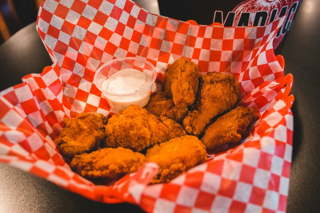 Crispy fried chicken in checkered basket with creamy dipping sauce.