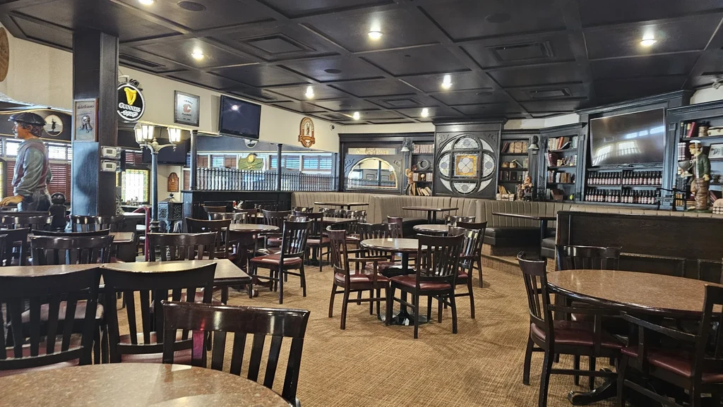 Traditional pub interior with wooden furniture, a dark bar, and two statues.
