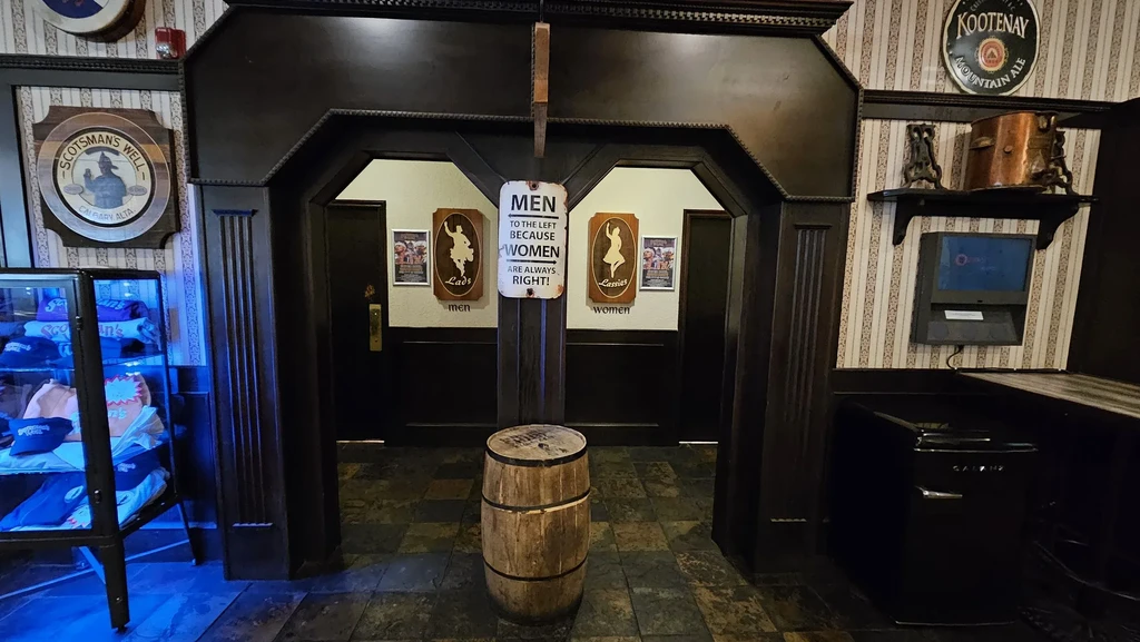 Pub restroom entrance, 'Lads' and 'Lassies' doors, humorous sign.