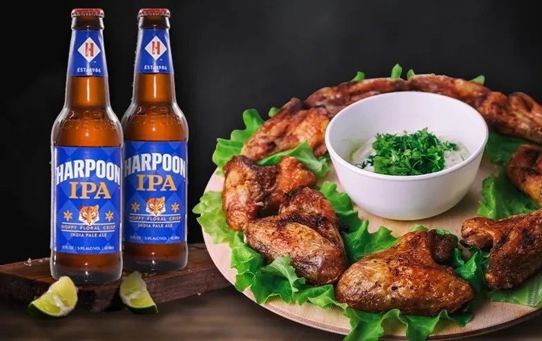 Harpoon IPA bottles, roasted chicken wings, creamy sauce, and lime wedges.