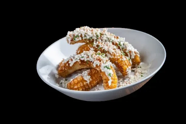 Corn segments with creamy sauce, crumbled cheese, red spice, and herbs.